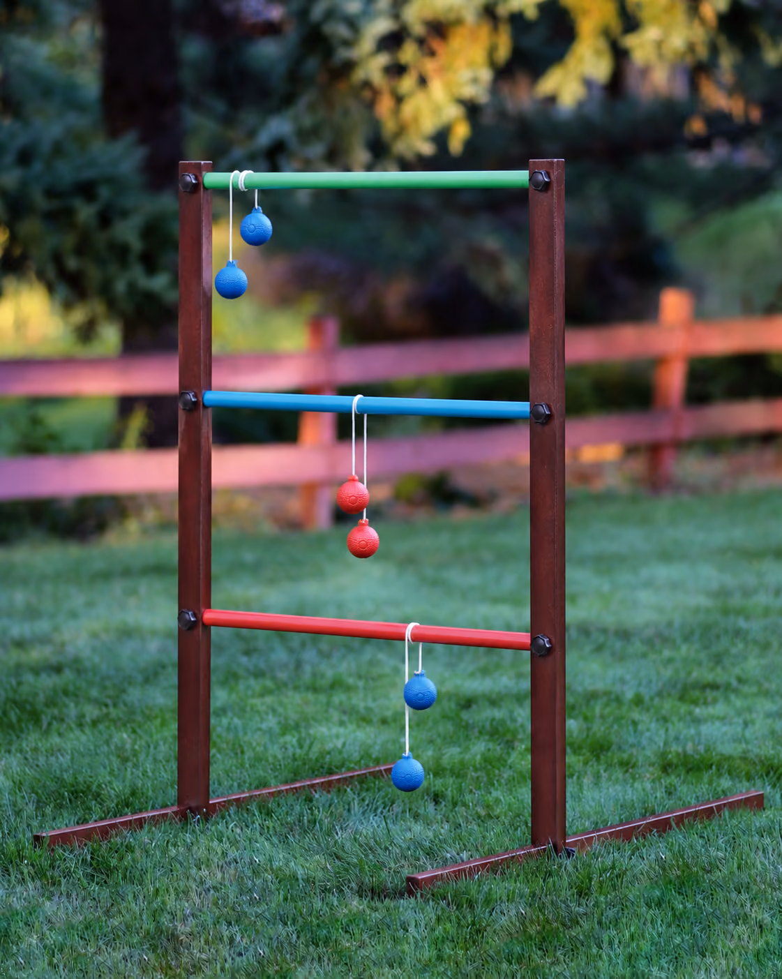 Wooden ladder ball game with colorful rungs and red and blue bolas on a lawn.