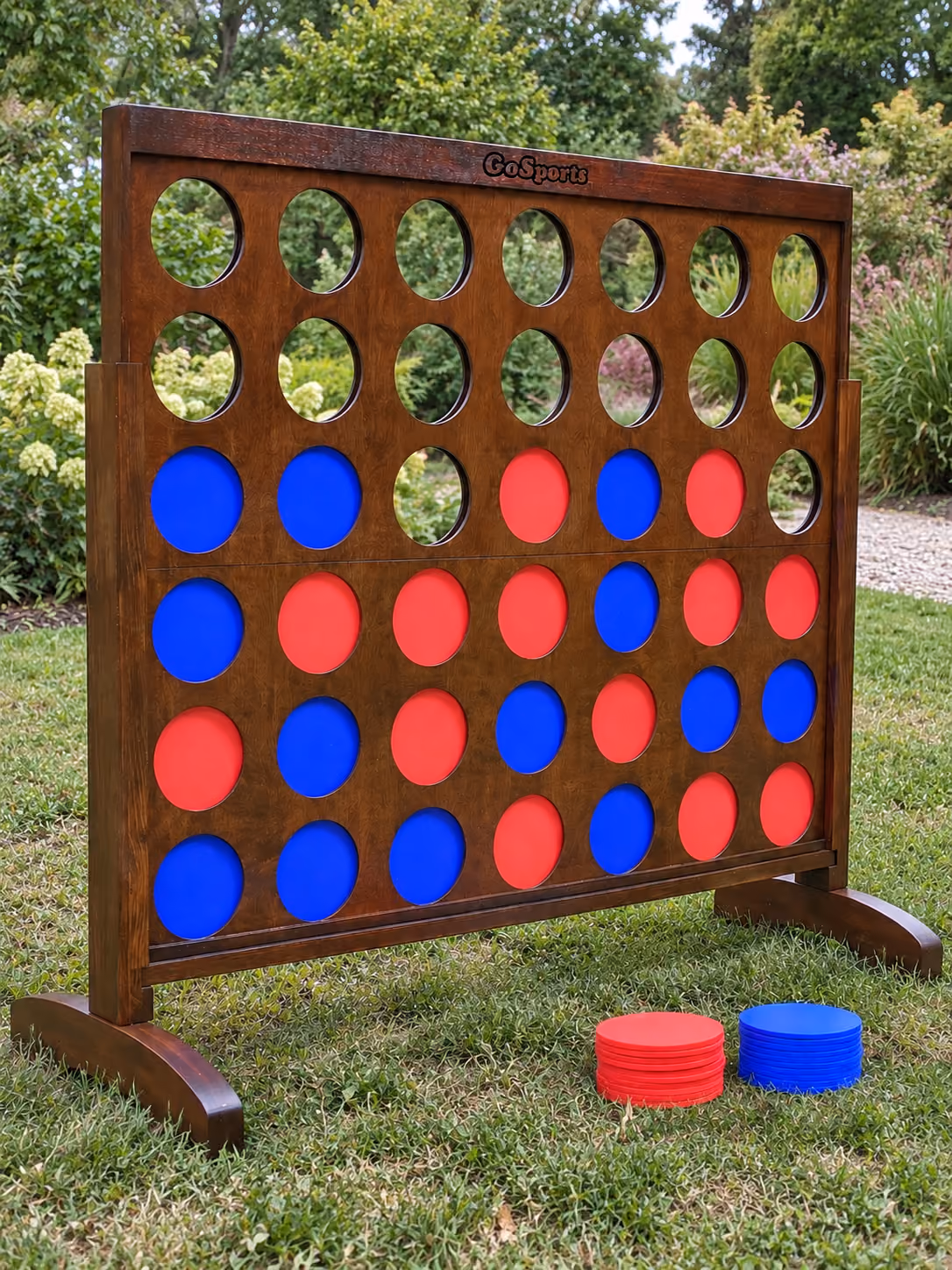 Giant wooden 4-in-a-Row yard game with red and blue discs, set up outdoors on grass.