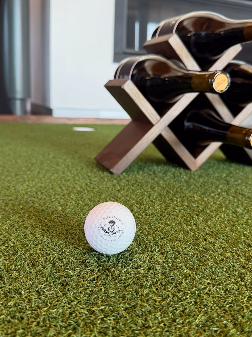 White golf ball on green artificial turf with Rex Hill Vineyards logo and text.