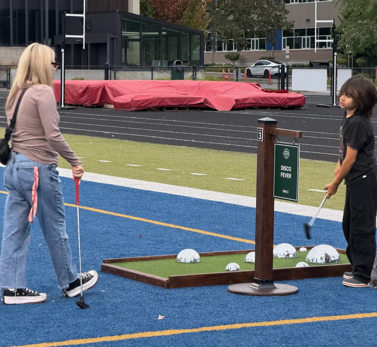 Two students standing beside a mini golf hole with white rock obstacles at Valley Catholic