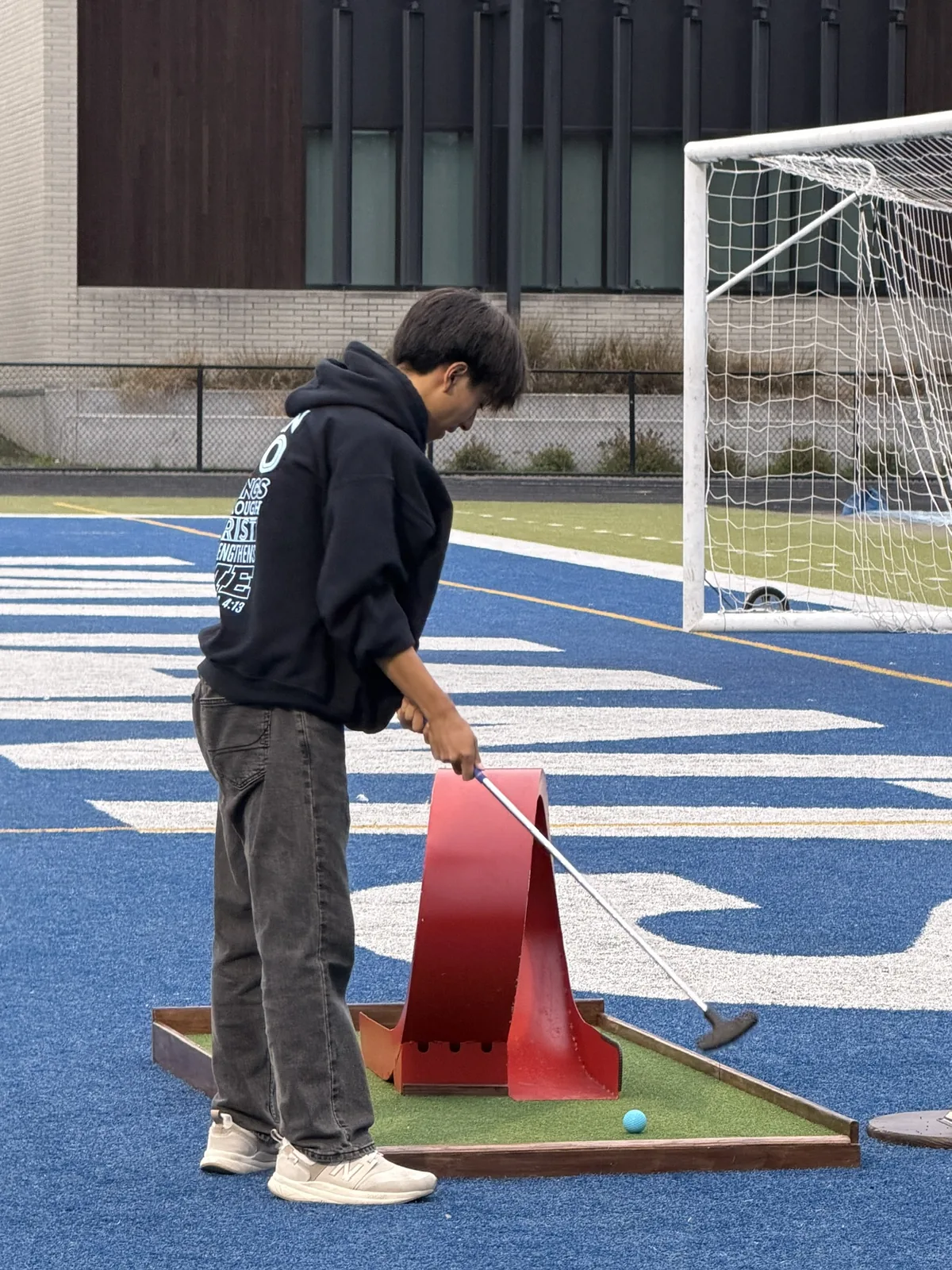Student putting through a red loop obstacle at Valley Catholic's homecoming carnival