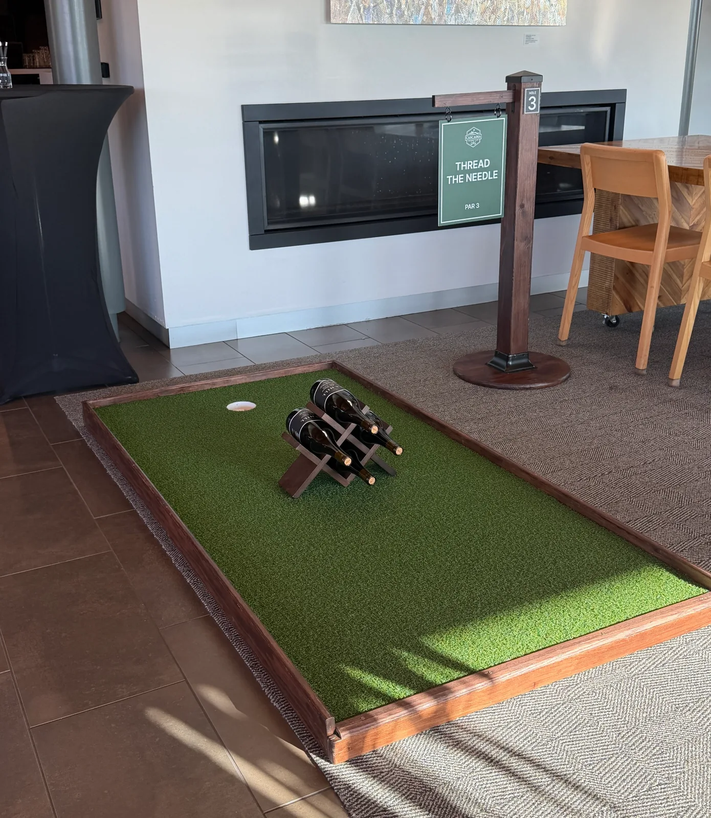 Indoor mini golf hole with a custom wine bottle obstacle at REX HILL