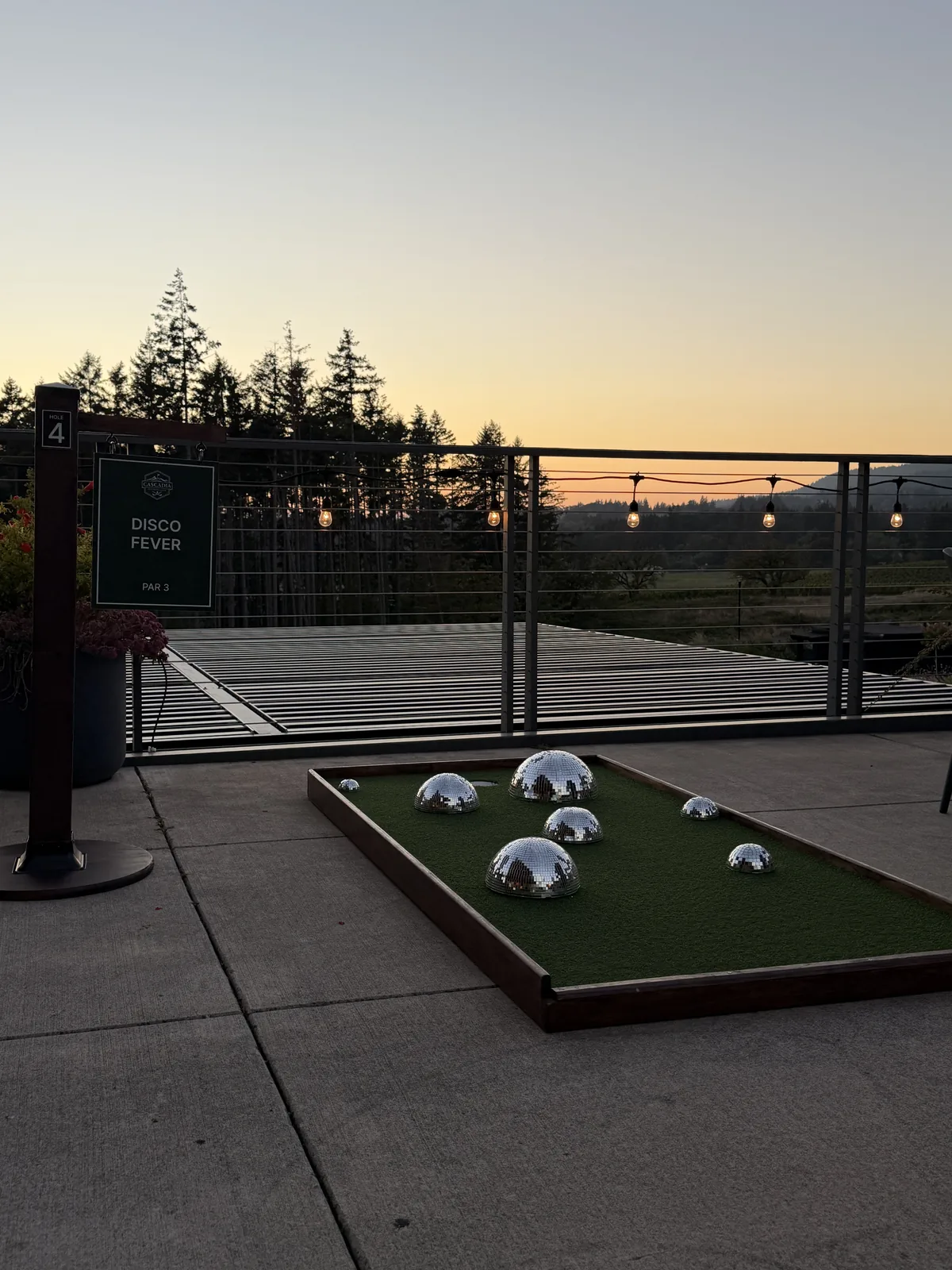 Mini golf hole on the REX HILL patio with vineyard views at sunset