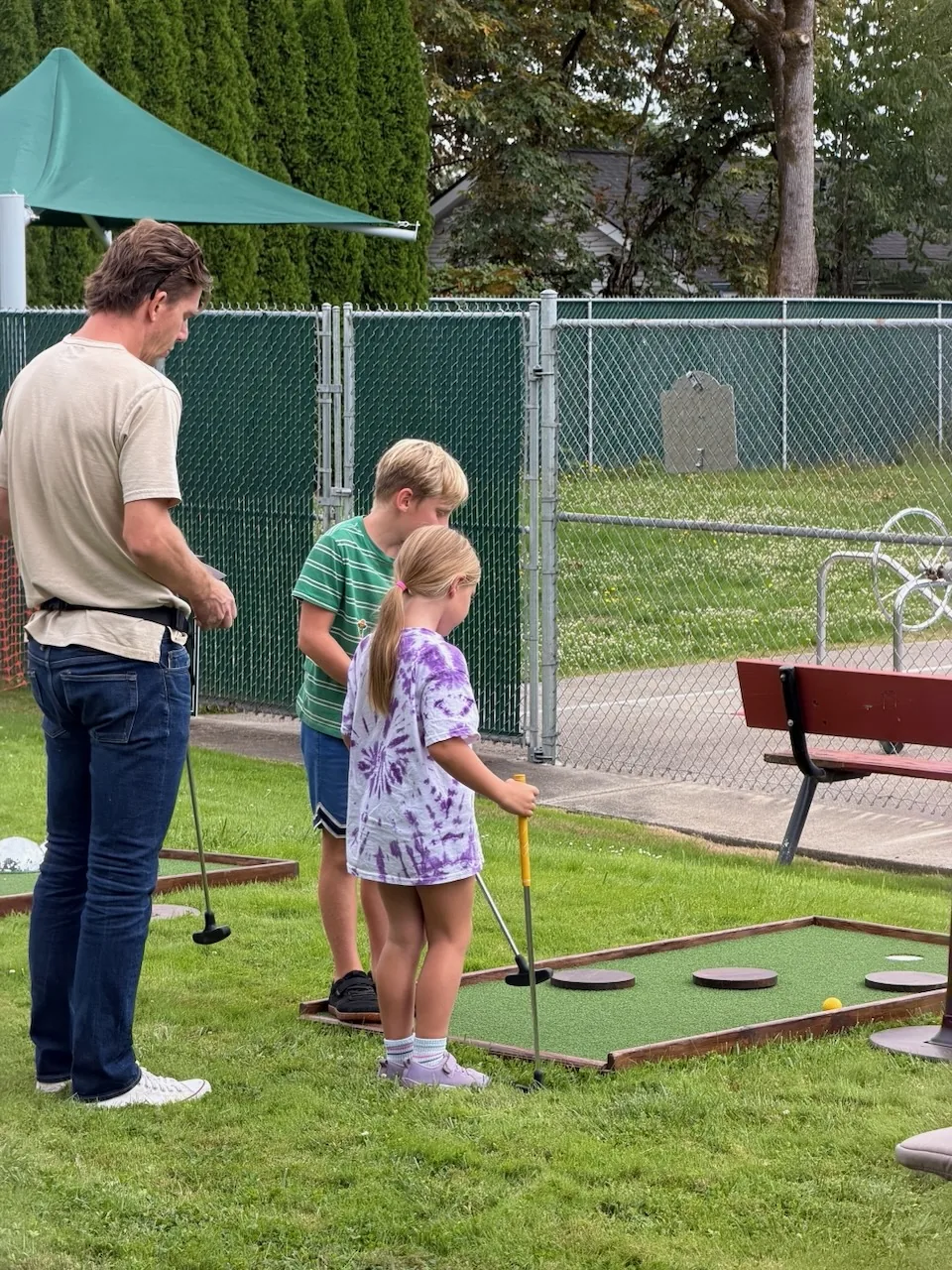 Family playing a mini golf hole with small obstacles at Carlton Crush