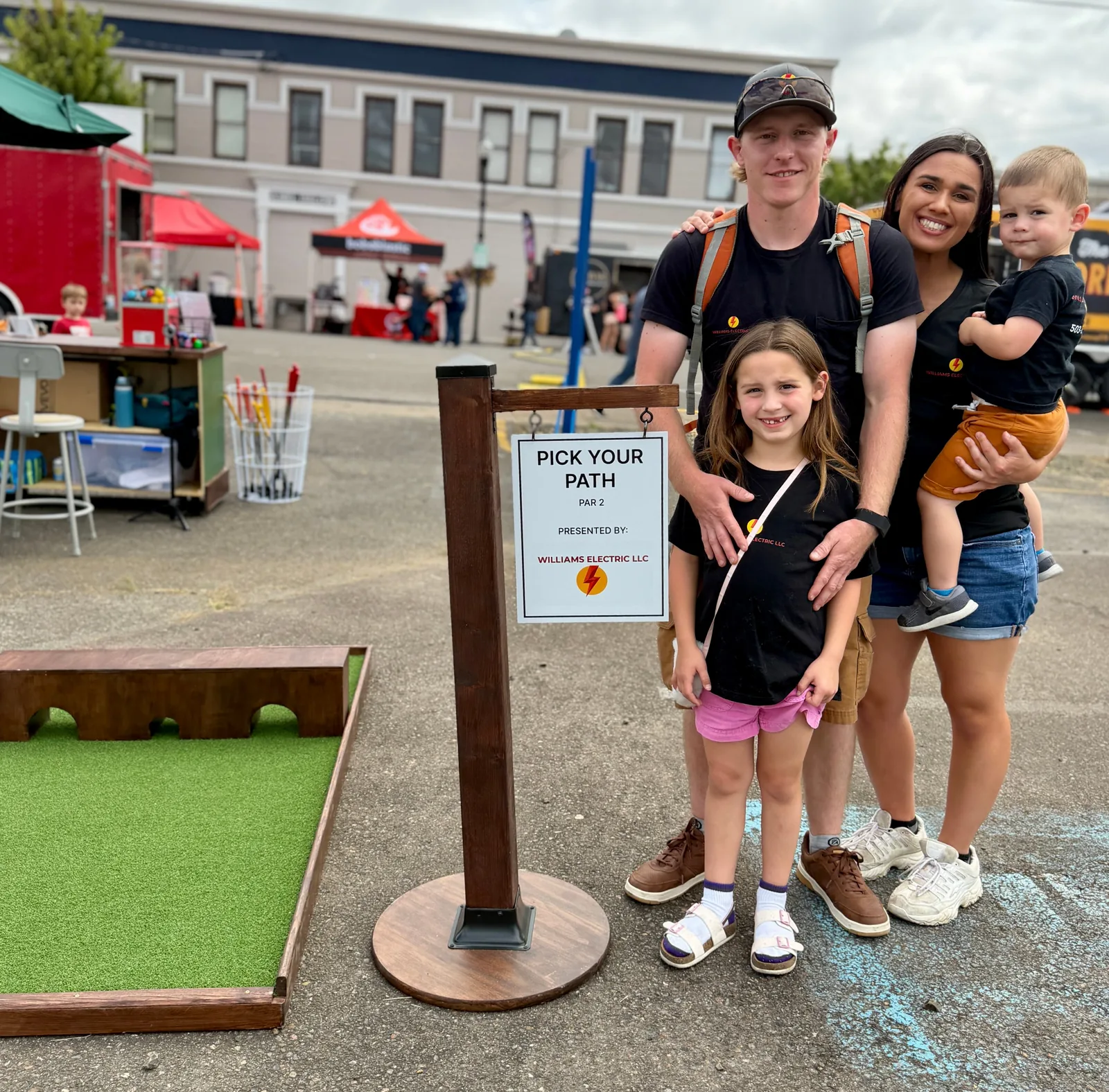 Williams Electric team beside their sponsored mini golf hole at Dallas Days