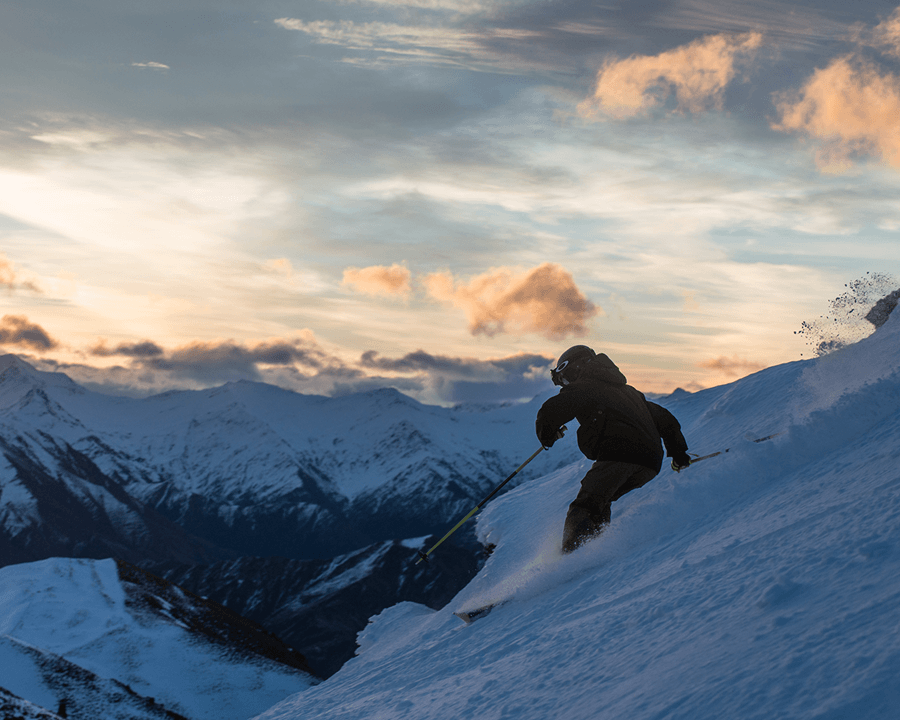 Person skiing on steep slope as the sunrises.