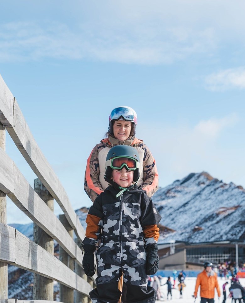 Mother & son on ski conveyor carpet.