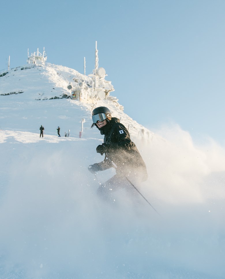 Skier turning on slope surrounded by cloud of snow.