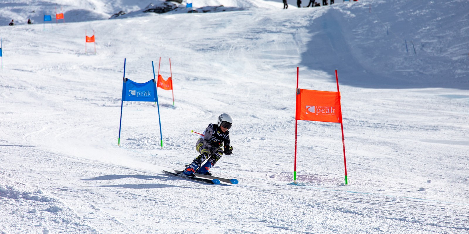 Skier in white helmet navigating a snowy slalom course with red and blue gates.