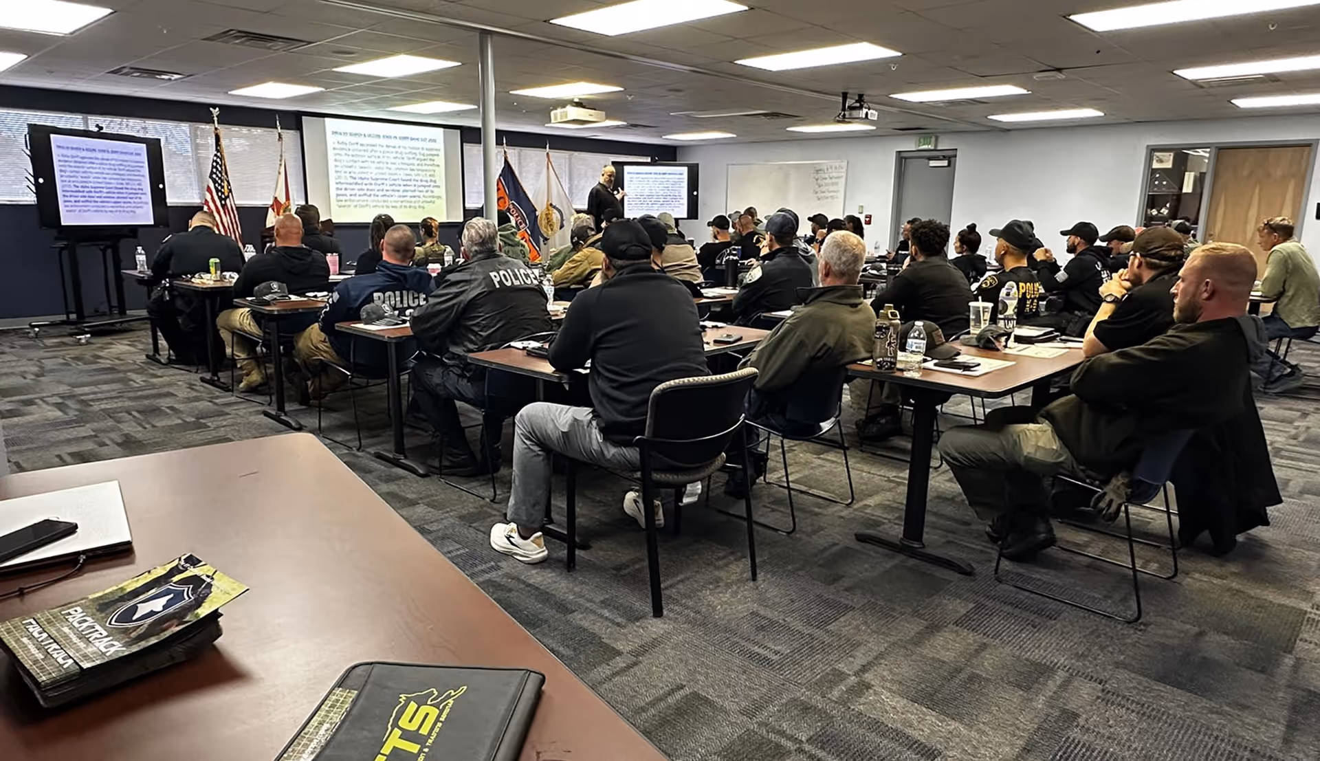 Group of police officers attending a classroom training session with instructor presenting in front.
