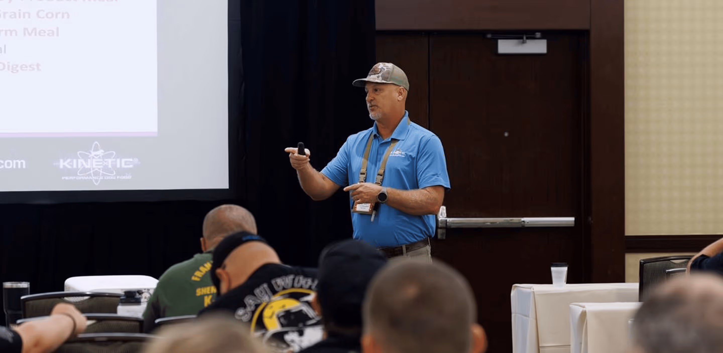 K-9 nutrition instructor in a blue polo presenting dietary information to handlers during a HITS conference seminar