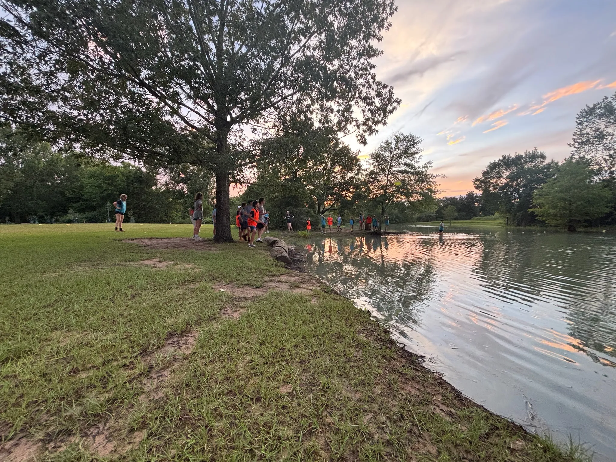 Nature Camp campers gathered along the edge of the pond at sunset