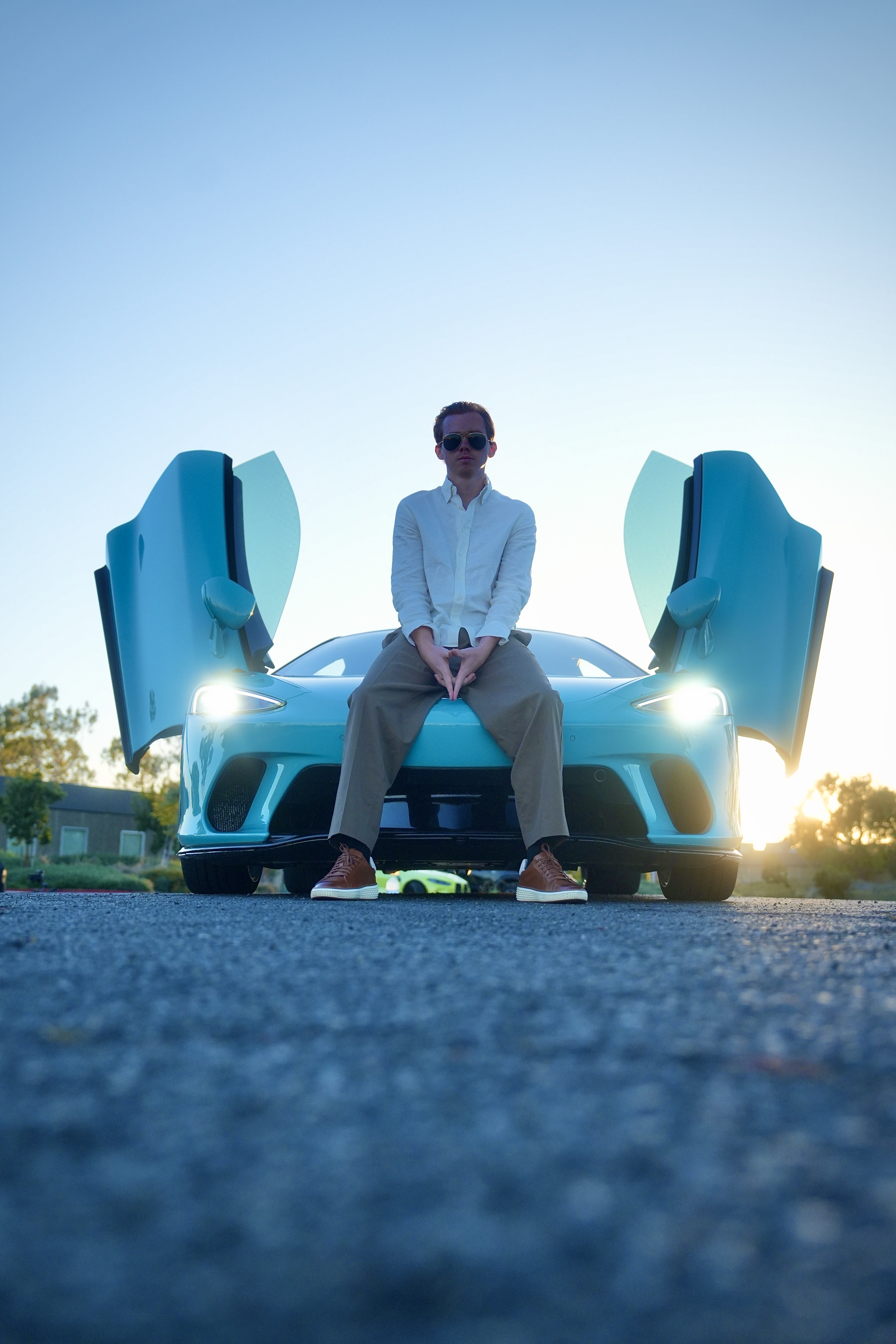 Ken Van Vorhis, founder of Prometheus Exotics, seated on a light blue McLaren with its doors raised at sunset in Orange County, California