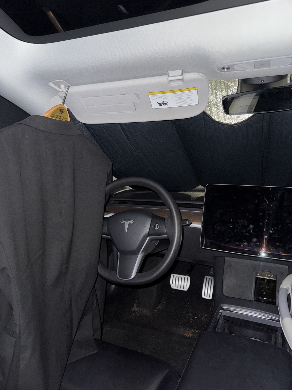 The inside of Ken Van Vorhis's Tesla with a sunshade across the windshield and a suit jacket hanging by the door, the car he lived out of while building Prometheus Exotics