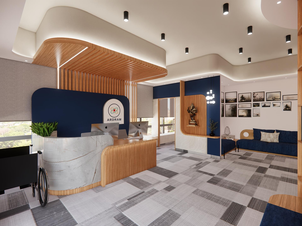 Modern reception area with curved wood desk, blue accents, computers, seating, and framed wall photos.