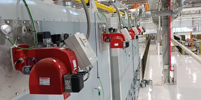 Reihe roter Industrieanlagen mit Maschinen und Kabeln in einer sauberen Fabrikumgebung.
