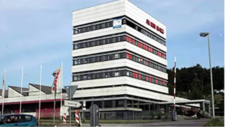 Bürogebäude mit mehreren Etagen und Straßenschild vor blauem Himmel.
