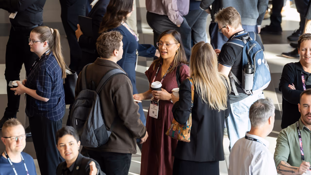 People in business attire networking and talking at a conference or event holding coffee cups.