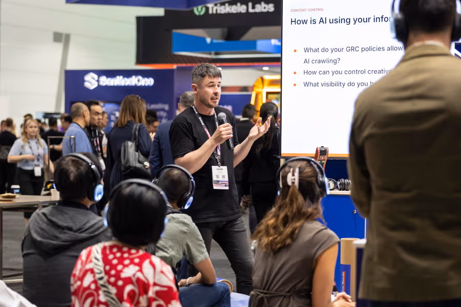 Man with microphone giving a presentation on AI to seated attendees at a conference or expo.