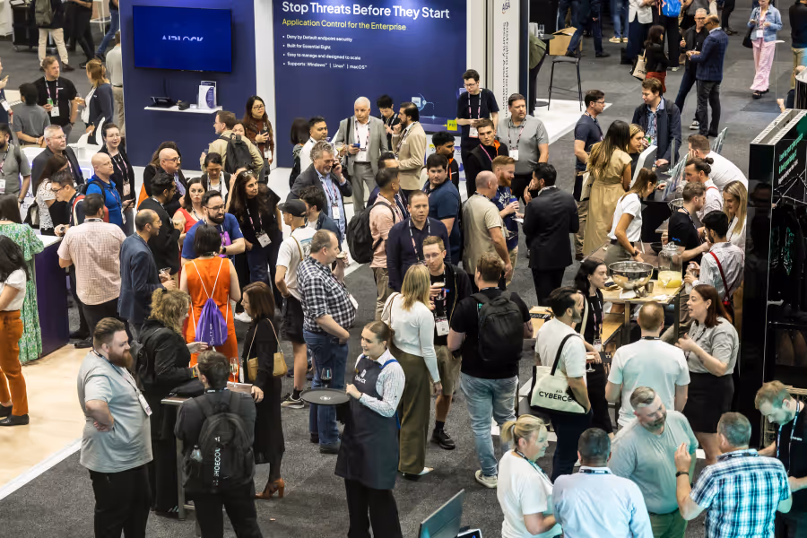 Crowd of people networking and visiting booths at a technology conference or trade show.