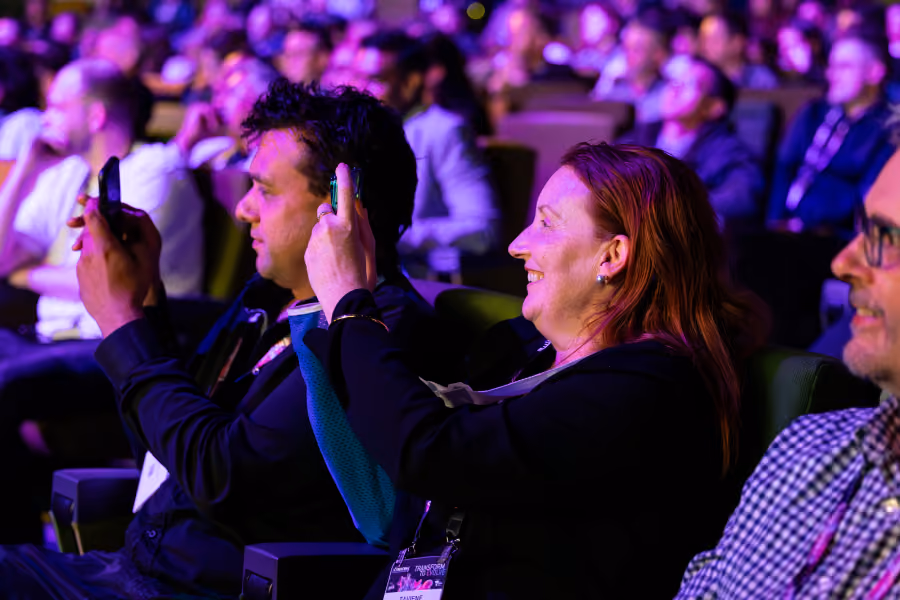 Delegates photographing the stage on their phones from the audience at CyberCon