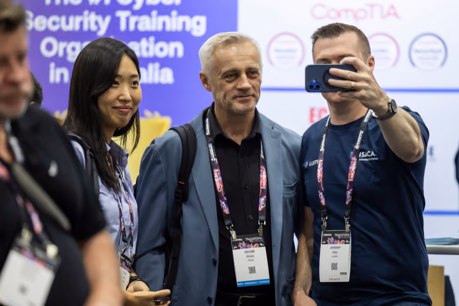 Delegates taking a selfie at an exhibitor booth at CyberCon
