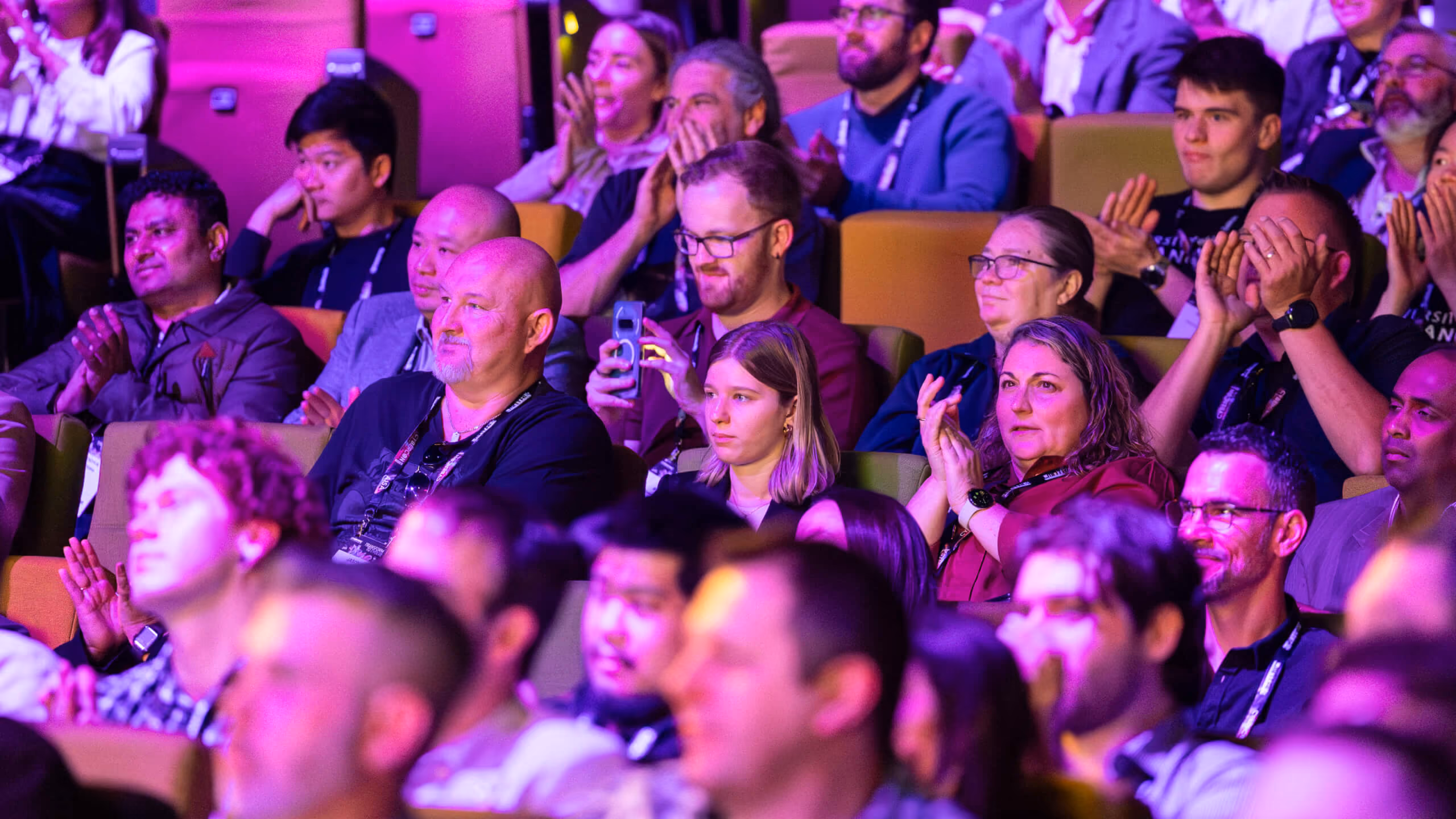 Audience applauding during a session under purple stage lighting