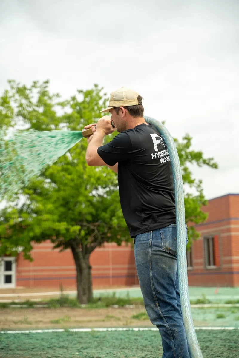 Fox Hydroseeding technician applying hydroseed near commercial property