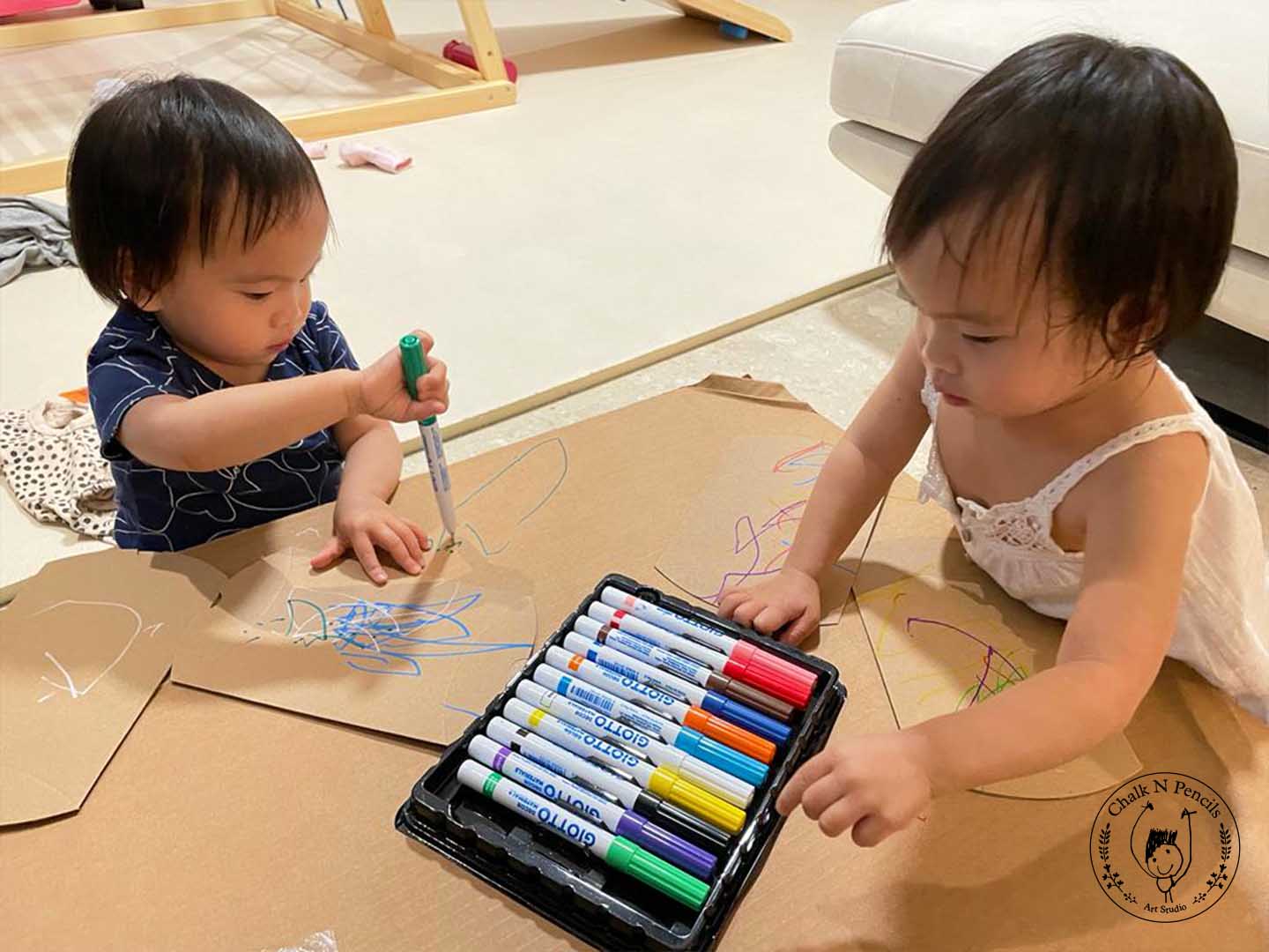 Toddler making energetic scribbles at a Chalk N Pencils class