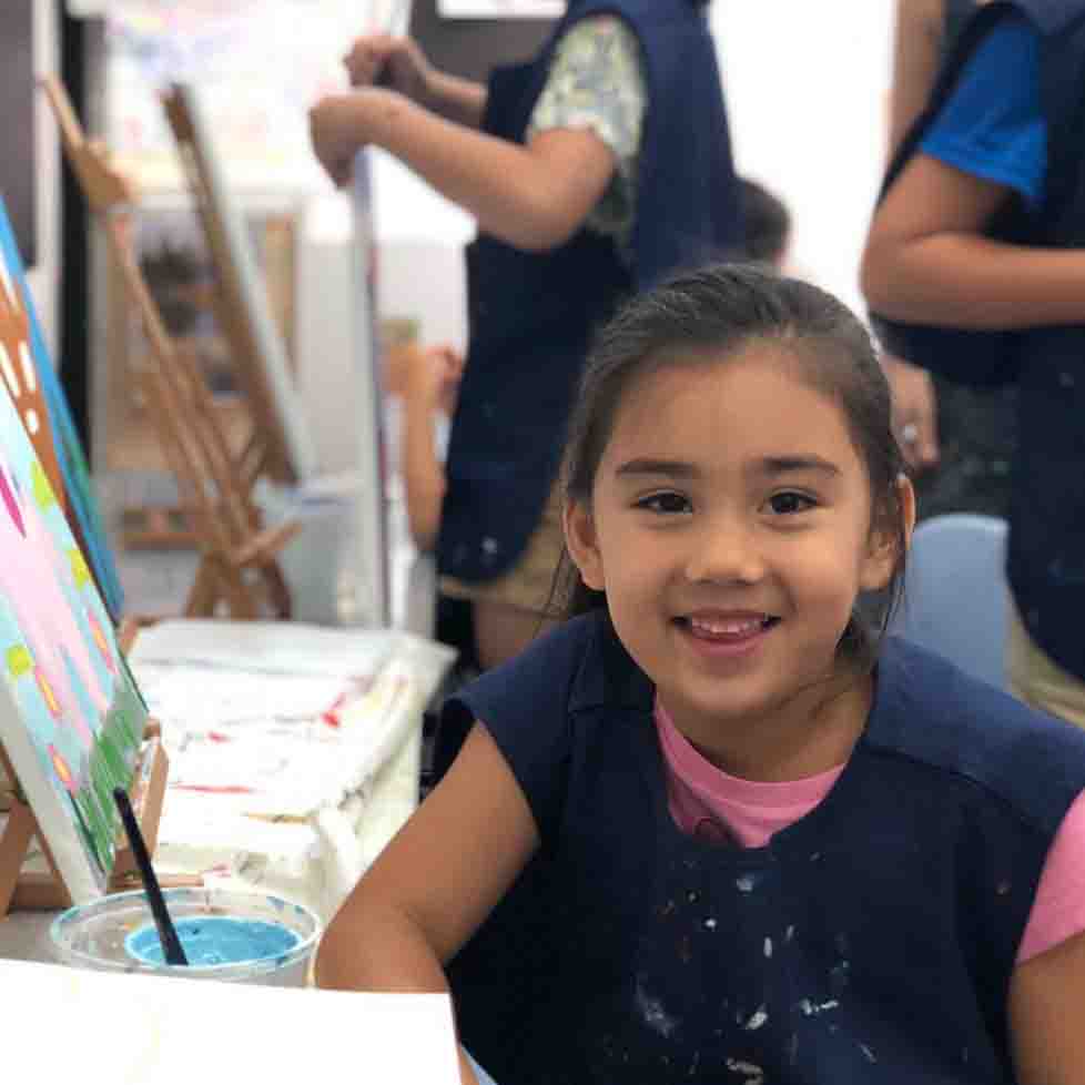 A happy child holding up their artwork in class
