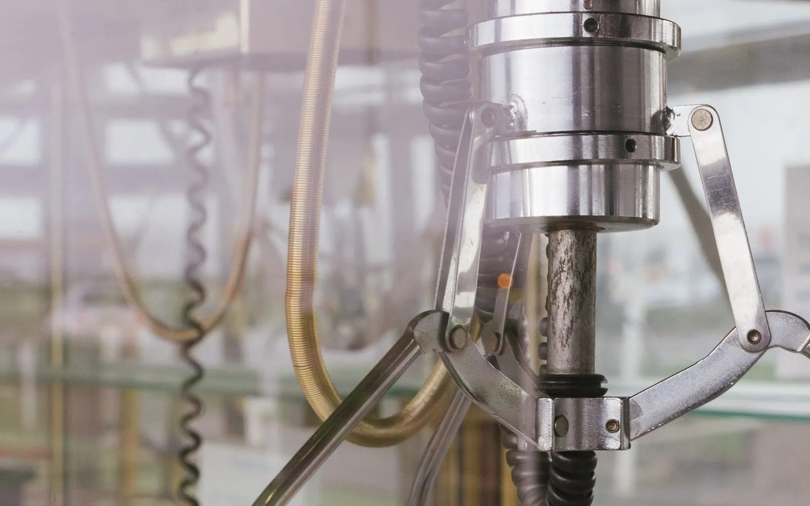 Close-up of a pneumatic gripper head with its jaws open above a stack of sheet material