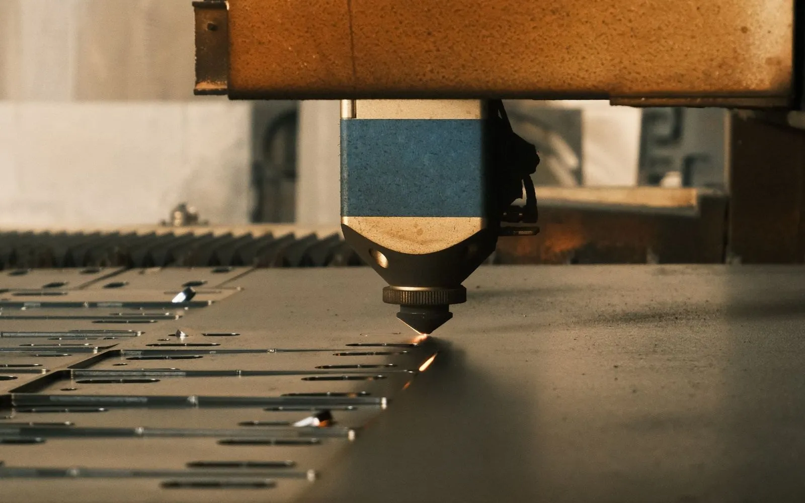 Cutting head working across sheet metal on a machine bed, sparks falling below the table