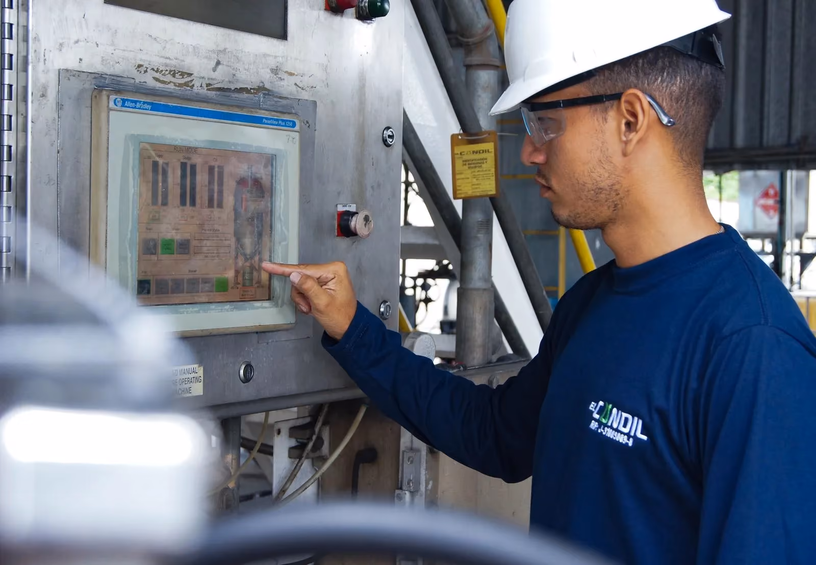 Engineer operating a machine control panel on the factory floor