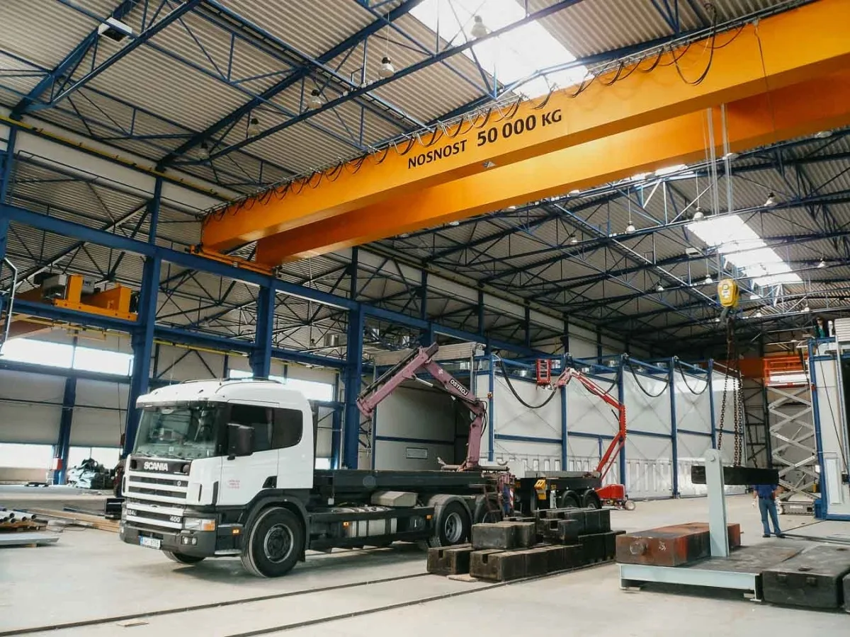 Vnitřek průmyslového skladu s mostovým jeřábem a nákladním autem Scania.