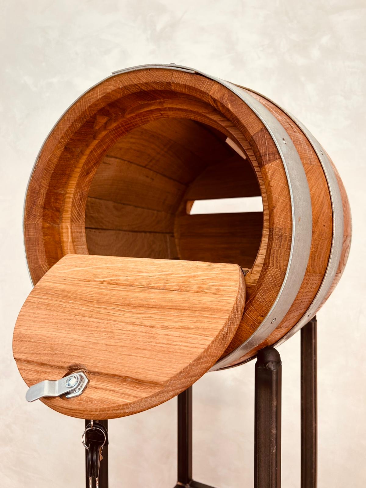 Open wooden barrel mailbox mounted on a metal stand with keys hanging from the latch.