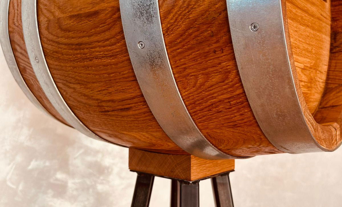 Close-up of a wooden barrel with metal bands on a wooden and metal stand.
