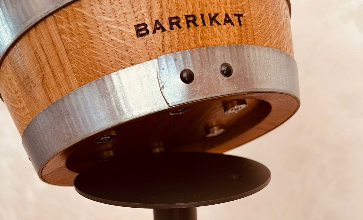 Close-up of a wooden object with metal band and screws labeled BARRIKAT.