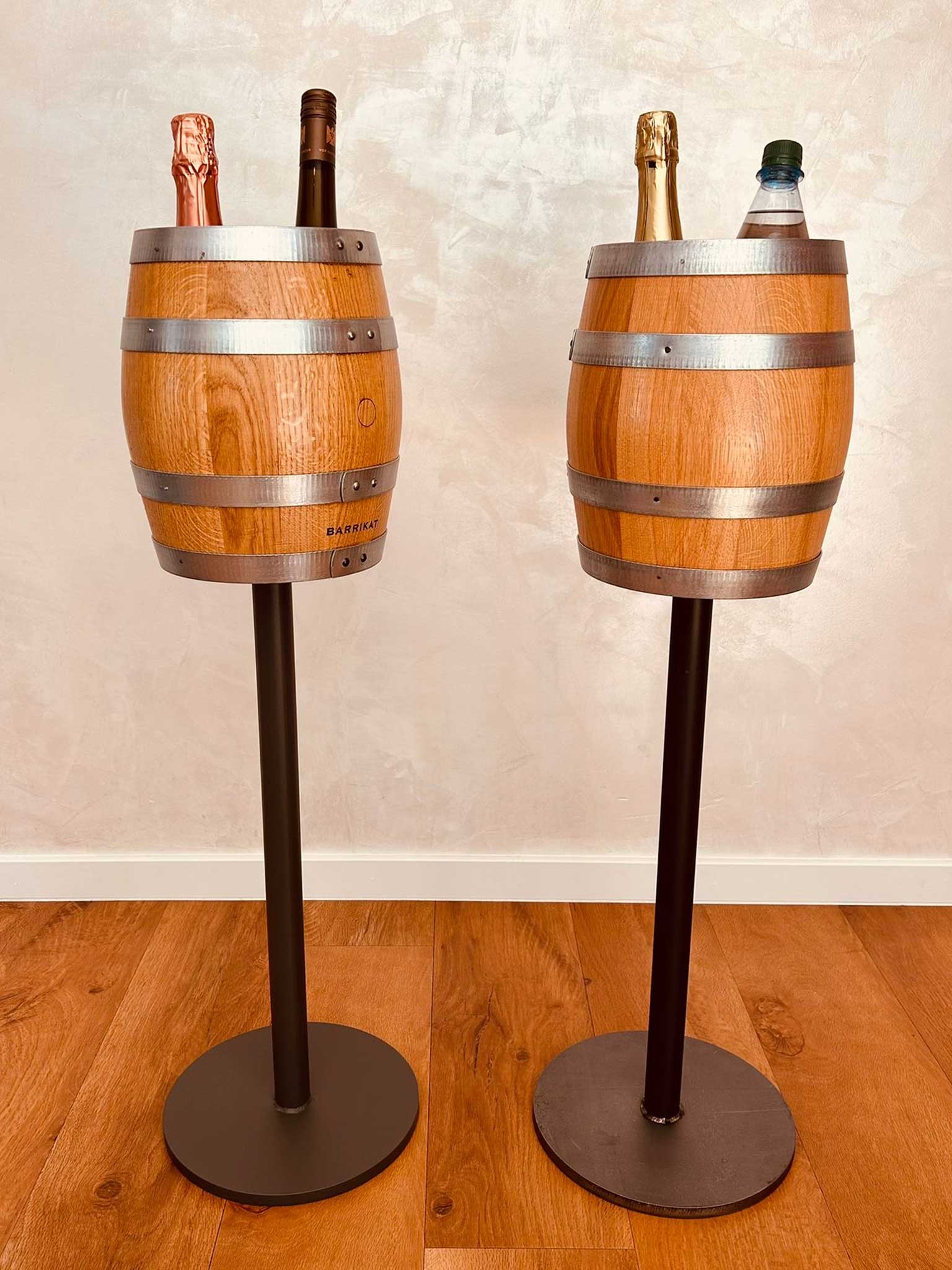 Two wooden barrel-shaped drink holders on black stands with bottles of wine and water inside.