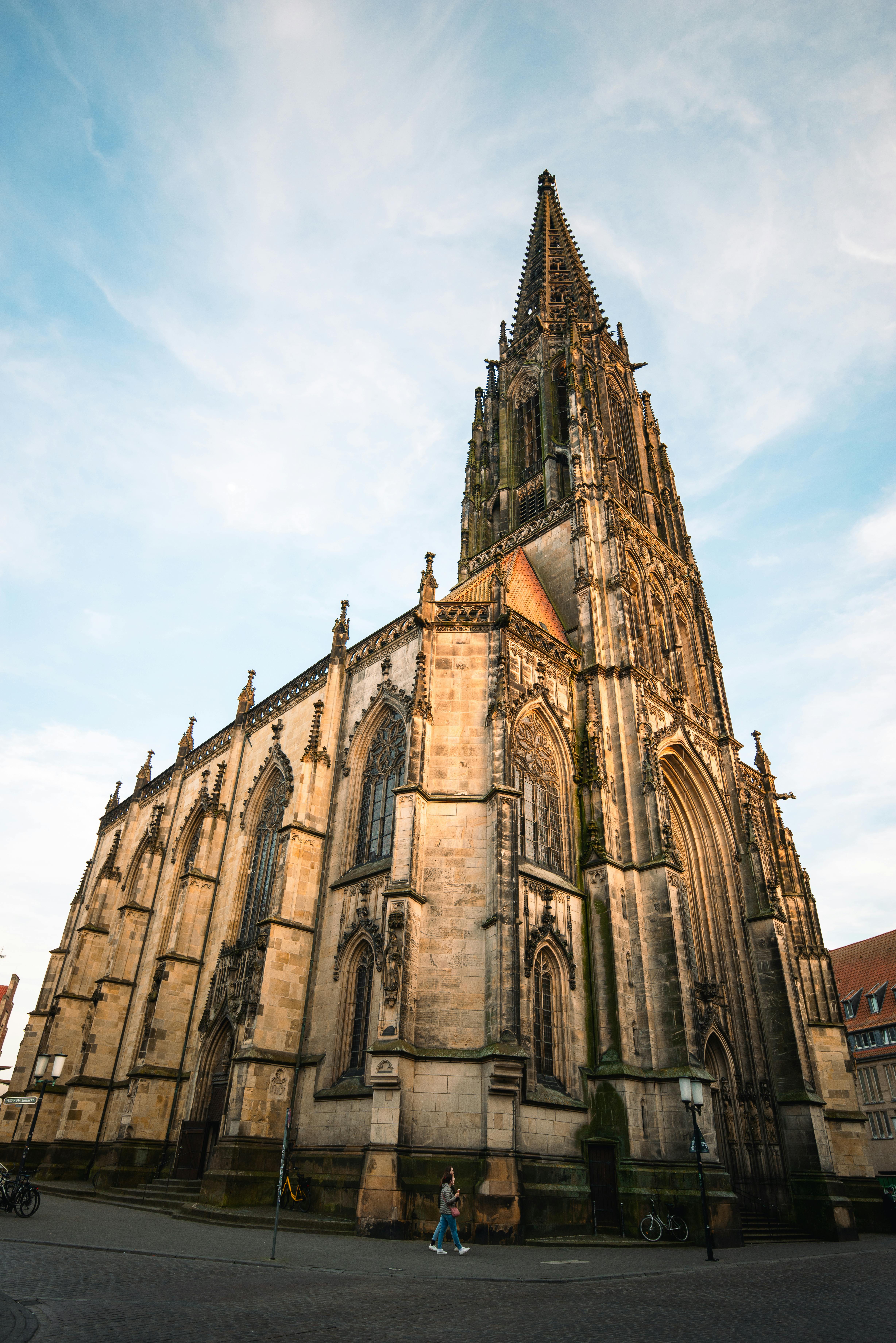 Large Gothic-style church with tall spire and intricate stonework under a blue sky.