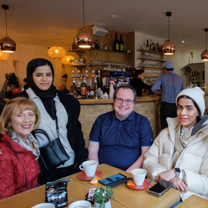 A group of four students sitting at a restaurant table smiling.