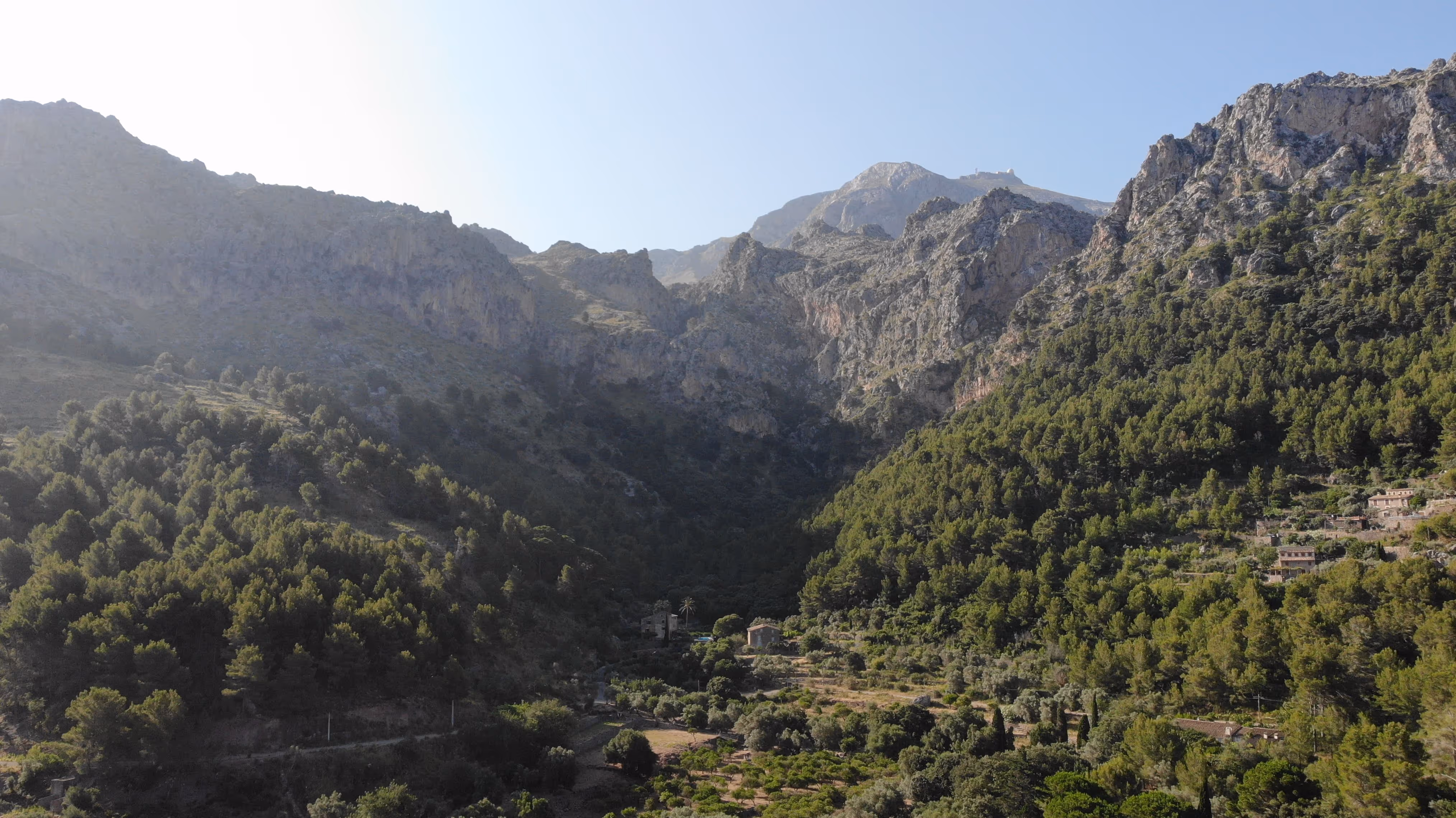 View over the green Tramuntana landscape near Cala Tuent with terraced hills and Mediterranean vegetation.