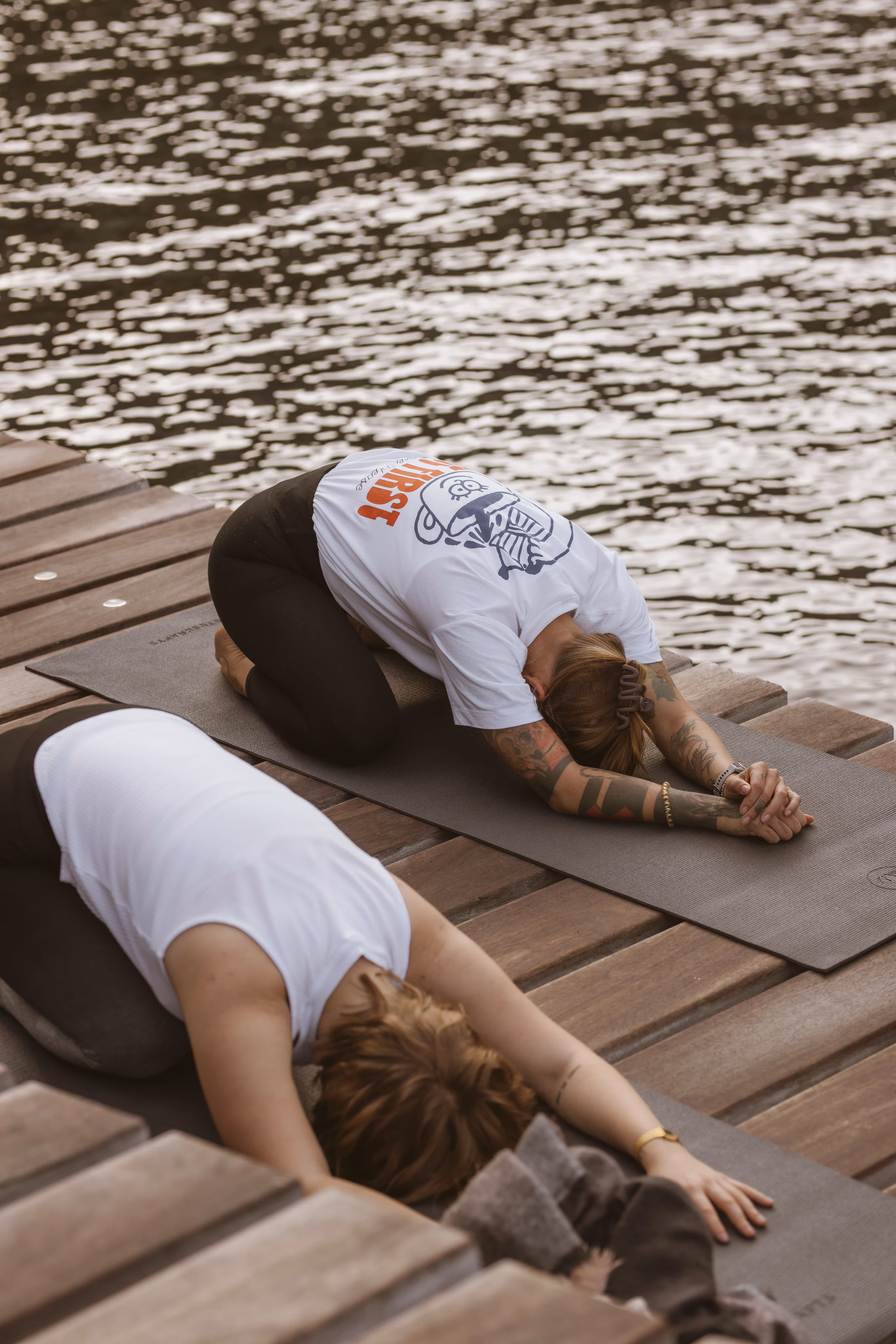 Yoga participants at Finca Higo practicing yoga on a wooden pier at Cala Tuent, resting in a child’s pose by the water.