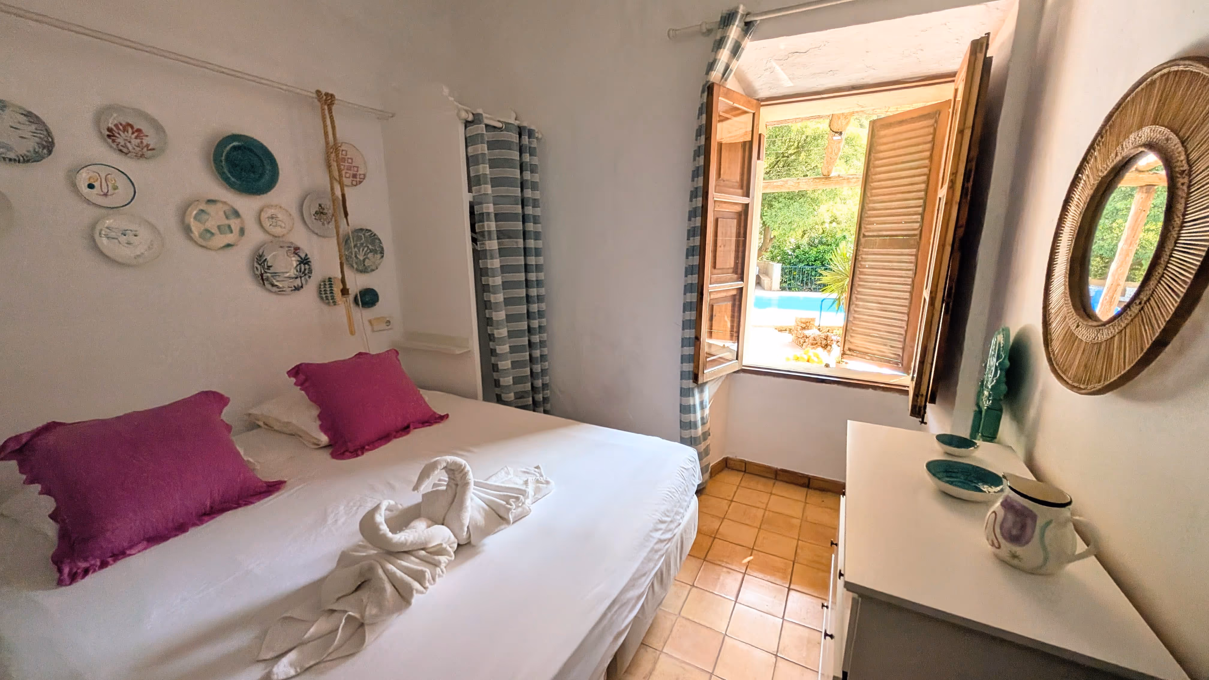 Ground-floor bedroom at Finca Higo with a large open window overlooking the pool, featuring a double bed and bright, rustic decor.