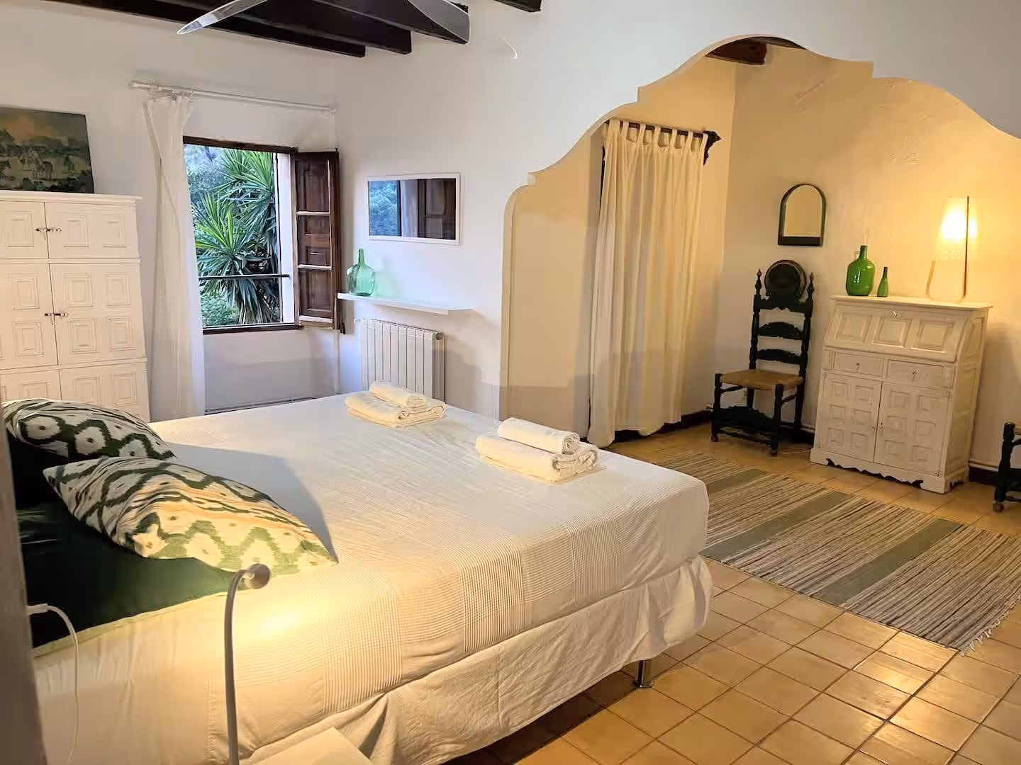 Spacious open room with a large double bed, tiled floor, and an open window overlooking greenery at Finca Higo.