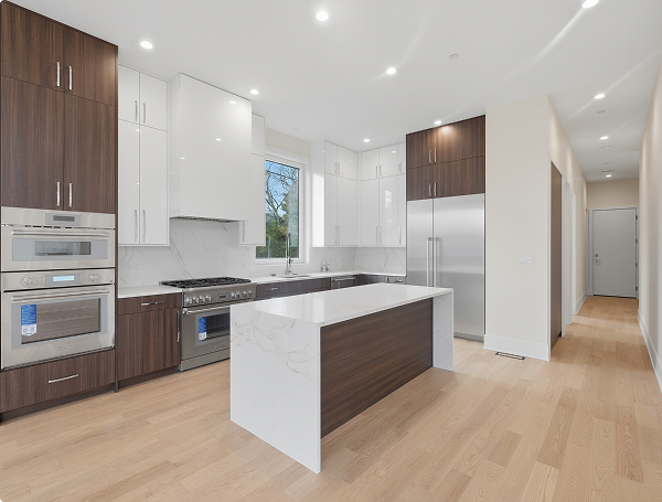Modern kitchen with wood and white cabinets, a marble island, stainless steel appliances, and hardwood floors.