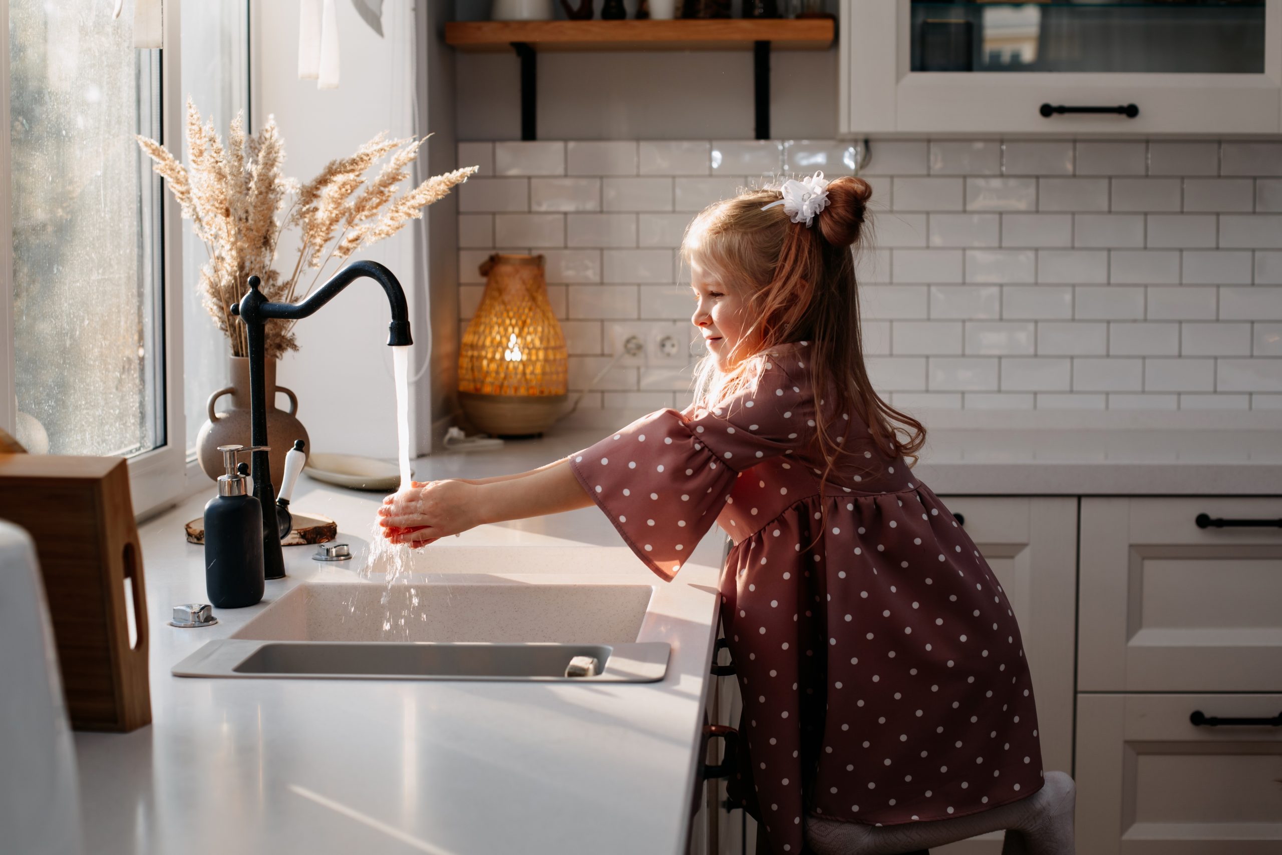 Young girl washing her hands at the kitchen sink