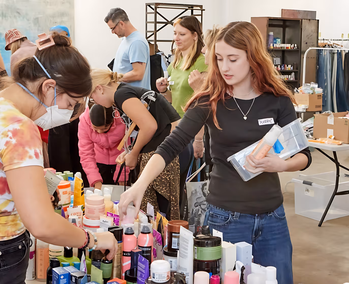 People selecting various personal care products from tables at a community event.