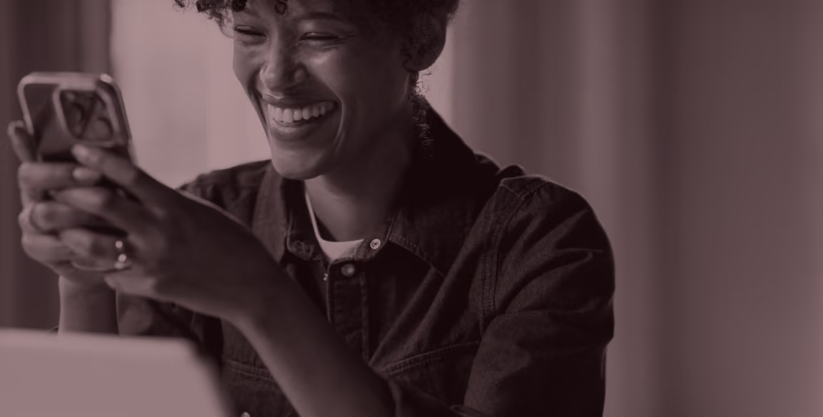 Smiling person looking at a smartphone held with both hands.