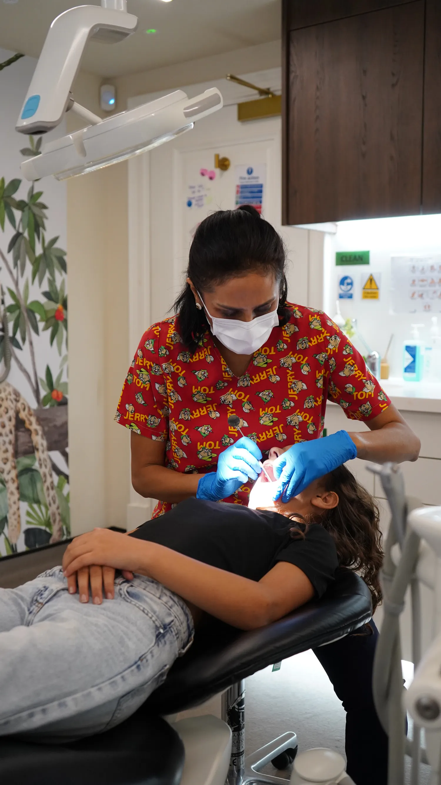 Dentist in a red Tom and Jerry shirt examining a child’s teeth at Clarendon Dental Spa in Leeds.