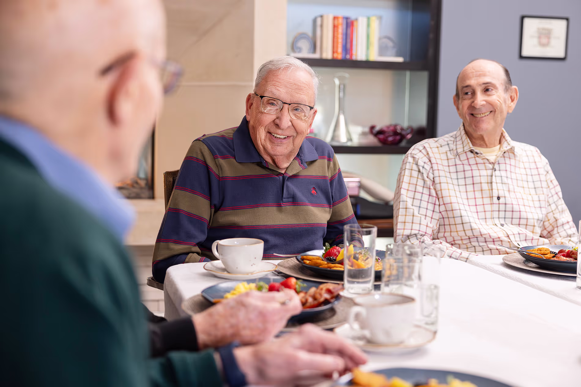 Group of senior men enjoying breakfast together, sharing conversation and laughter in a casual, friendly setting.